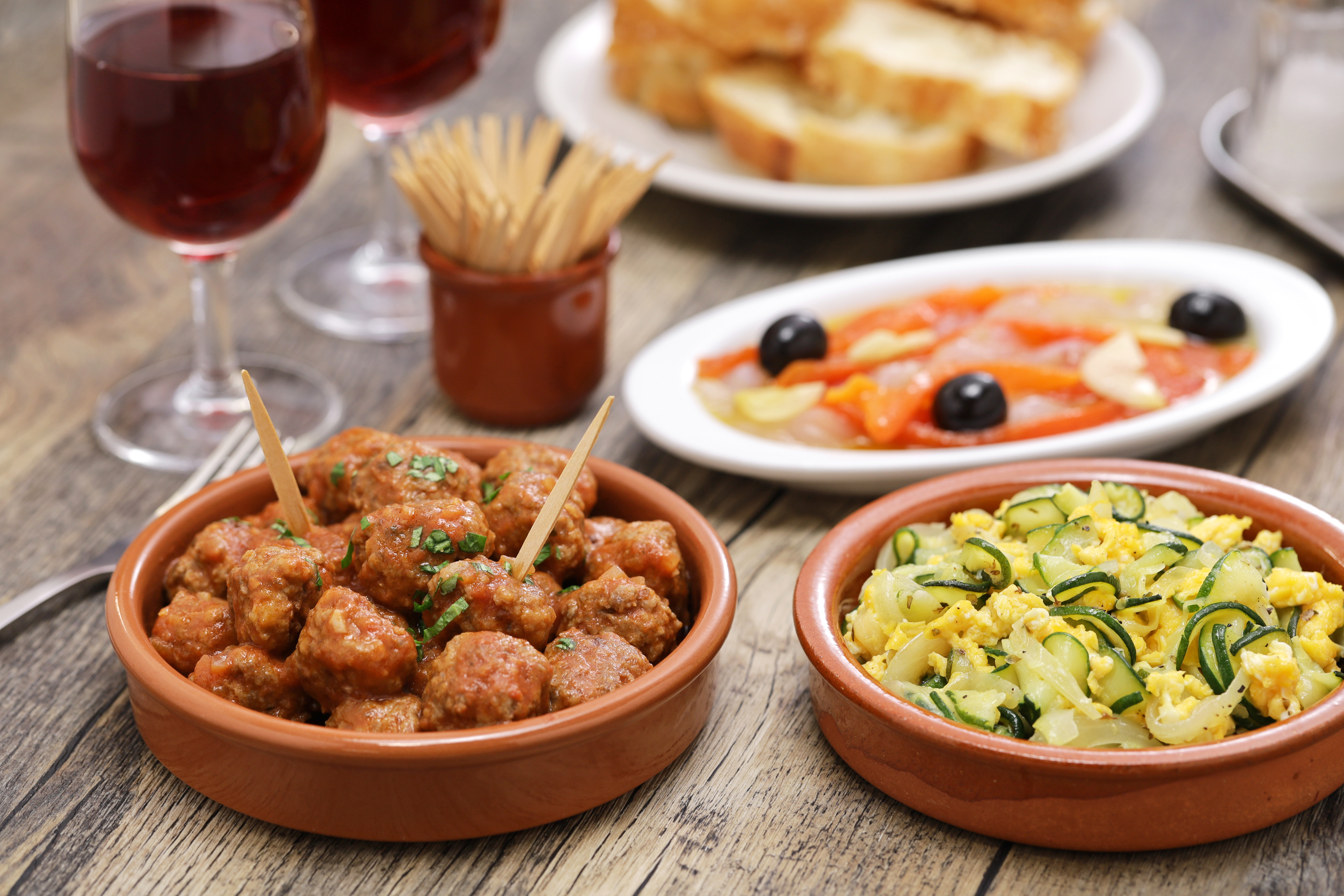 A table of shared tapas-style dishes, including courgette and egg zarangollo, meatballs, bread and wine, evoking Murcia&rsquo;s informal bar dining culture.